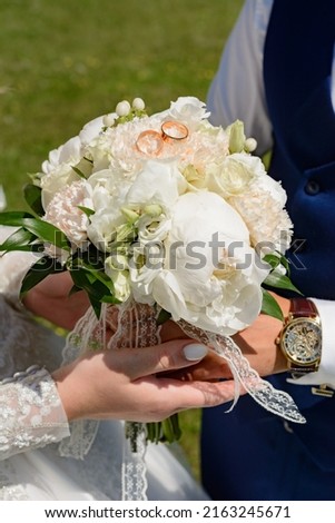 The bride holds a bouquet in her hands, standing next to the groom, a sunny wedding day.