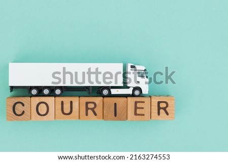 Toy truck with wooden box on turquoise background. Courier