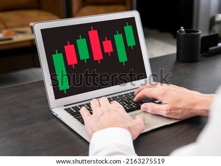 Businessman working with candlestick graph at laptop. Stock value behavior analysis. Investment, analytics and trade concept. Man hands at keyboard. High quality photo