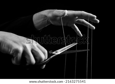 Man cutting strings on hands with scissors. Abuse, violence, slavery cessation. Overcoming addiction and mental health problems. Getting rid of manipulation. Black and white. High quality photo Royalty-Free Stock Photo #2163275541