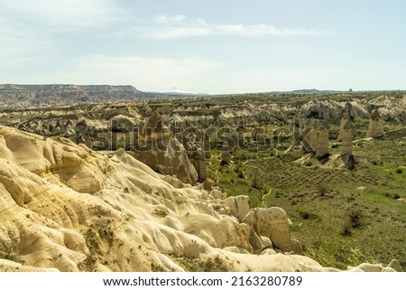 The typical rock formations of Cappadocia with fairy chimneys, desert landscape and Erciyes mountain on the background  in Love Valley , Goreme, Nevsehir, Kapadokya. Popular travel destination.