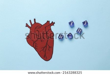 Healthy heart concept. Paper-cut anatomical heart with dice on a blue background