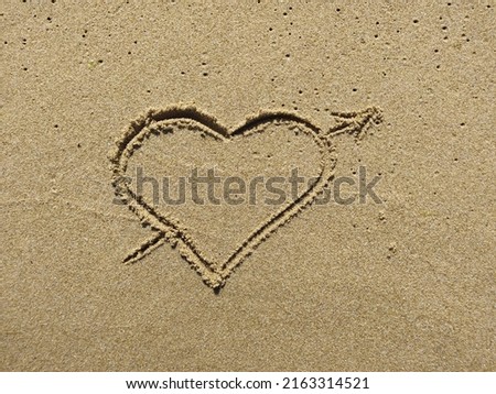 Picture of heart handwritten on sand. Sign of love on sunny outdoor background. 