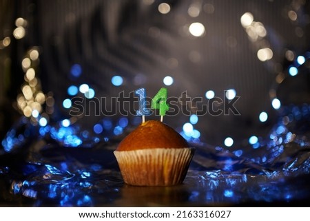 Digital gift card birthday concept. Tasty fresh homemade vanilla cupcake with number 14 fourteen on aluminium foil and blurred dark background in minimalistic style. High quality image