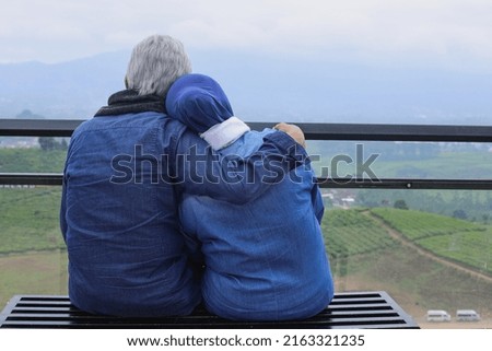 Back side of romantic mature couple hug each other and seeing landscape. Wife leaning on her husband's shoulder. Happiness elderly couple concept. 