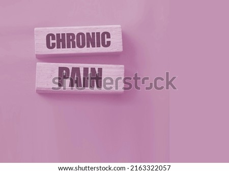 Chronic pain words on wooden blocks on red background. Medicine healthcare concept.