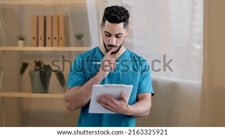 Hispanic physician male doctor man therapist medic wear uniform standing in hospital clinic writing notes fill medical form insurance notice detailed prescription receipt prescribe treatment patient Royalty-Free Stock Photo #2163325921