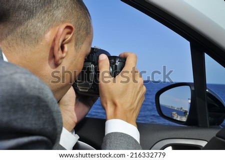 a detective or a paparazzi taking photos from inside a car