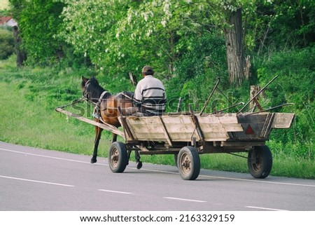A peasant on a horse with a cart on the road Royalty-Free Stock Photo #2163329159