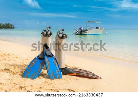 Scuba diving gear on display at pristine tropical beach diving holiday destination of Moorea, French Polynesia, with diving boat in the background, fins, dive tank and masks, sunny day blue skies Royalty-Free Stock Photo #2163330437