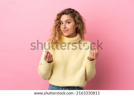 Young blonde woman isolated on pink background making money gesture but is ruined