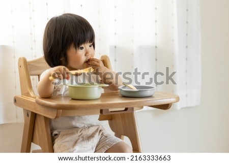 Baby sitting and eating (1 year and 10 months, girls, Japanese) Royalty-Free Stock Photo #2163333663