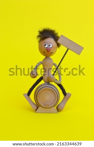 Wooden boy toy standing on a drum on a yellow background