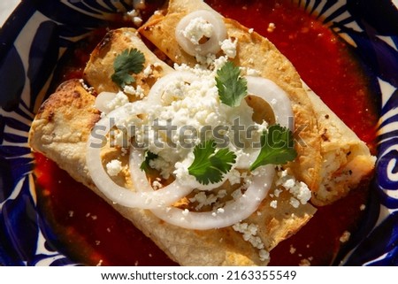 Fried potato tacos called flautas with red sauce and cheese. Traditional mexican food