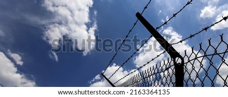 Сontour of barbed wire on background beautiful clouds and sky