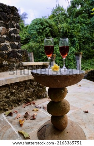 glasses of red wine and frangipani flower in the stone table on the tropics