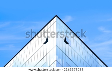 Symmetry and Low Angle view of modern Glass office Building with light reflection on surface against blue Sky background, manipulation techniques Royalty-Free Stock Photo #2163375285