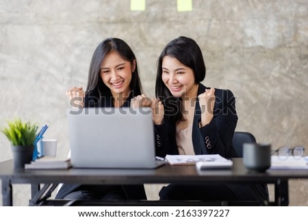 Happy excited Two Elegant Asian businesses woman in the office working with computer make raising hands to congratulate the winner gesture.