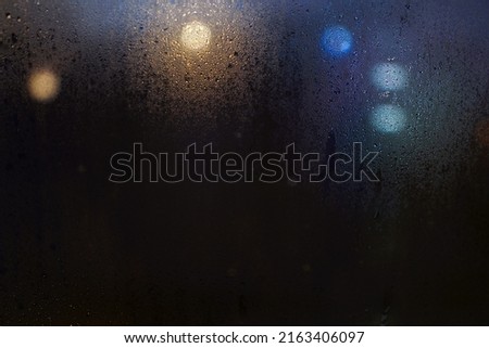 
Blurred image of glass window steam. At night, a round bokeh lights outside can be seen in the beautiful darkness.