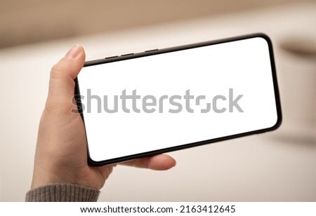 Mockup cell phone. female hand holding phone horizontally with blank white screen. Mockup phone horizontal. human left hand holding black horizontal mobile phone