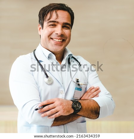 Male doctor standing arms crossed looking at camera smiling, portrait. Happy handsome professional medical occupation worker with a stethoscope provides consultation and treatment services at hospital