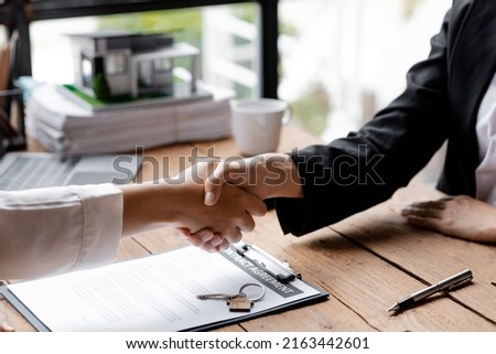 The salesperson of the housing estate in the project and the customer shake hands after successfully signing the contract. Concept of selling housing estates and real estate.