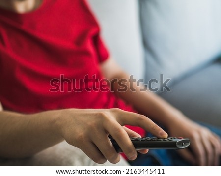 Sedentary man with red t-shirt changing television channel with the remote control. sedentary life concept Royalty-Free Stock Photo #2163445411