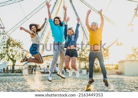 Group of young people jumping on the sand, friends having fun in a beach party, freedom and joyful summer image, london people traveling