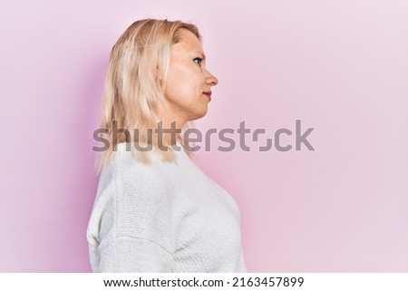 Beautiful caucasian blonde woman wearing casual winter sweater looking to side, relax profile pose with natural face with confident smile. 