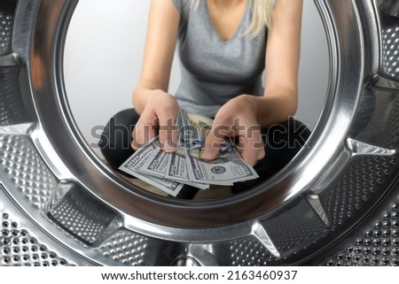 Women's hands hold money near the washing machine, a photo from inside the drum of the washing machine. Concept of payment, money laundering.