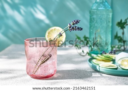 Cool lavender lemonade with lime slices and lavender flower on the table near pastel light blue background. Healthy organic summer soda drink. Detox water. Diet unalcolic coctail. Royalty-Free Stock Photo #2163462151