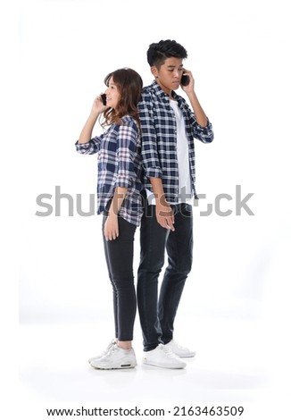 Full body young couple standing together posing in studio-gray background

