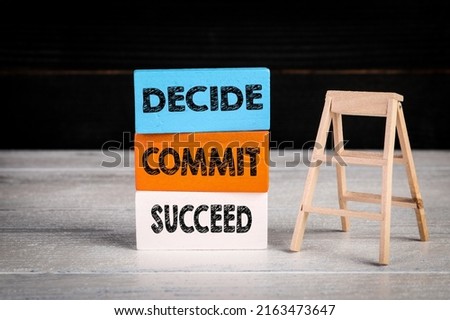 DECIDE COMMIT SUCCEED. Colored wooden blocks and stairs on a white and dark background.