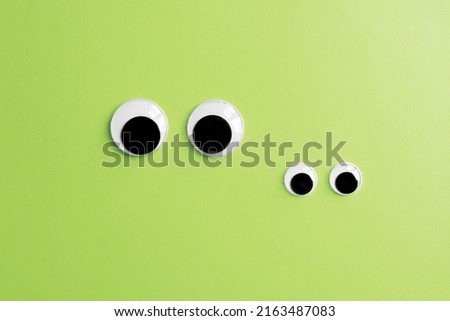 inivisible frog family - two pairs of googly eyes on green color paper background