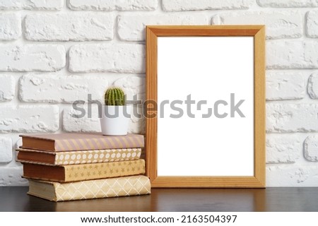 Books with picture frame on wooden table copy space