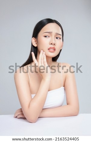 Young Asian woman touch and worry about her face. Acne, pimple, clear and clean, oily, dry skin concept.