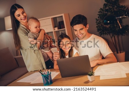 Photo of funny positive mother father little children booking modern device late night indoors room home house
