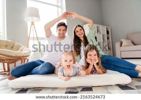 Photo of dreamy adorable couple two small kids lying mattress showing arms roof indoors house home room