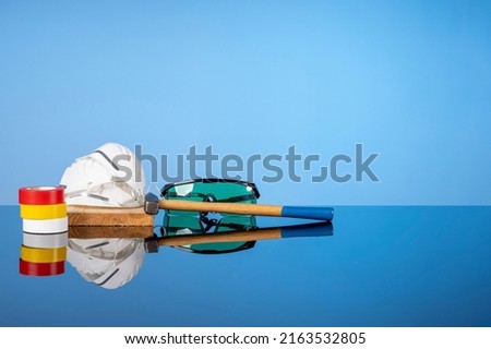 Tools for repair and construction, a hammer, colored electrical tape, goggles and a mask. Do it yourself concept, sale of goods for renovation and construction, home renovation services.
