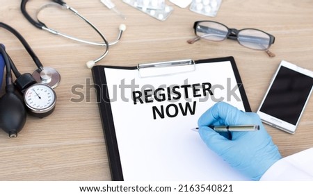 Register Now text on a piece of paper writes a doctor's hand on a table, a medical concept