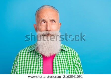 Portrait of minded aged man look interested empty space hesitate isolated on blue color background
