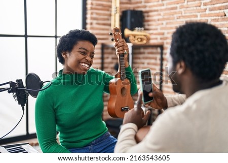 African american man and woman music group make photo holding ukelele at music studio