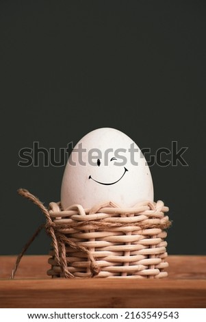 White egg in a small egg basket and a smiley face icon.