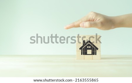 Home protection, insurance, loan, mortgage and buy a real estate concept. Showing hand to protect home on wooden cubes on grey background. Stay home stay safe concept. Real estate consulting service. Royalty-Free Stock Photo #2163555865