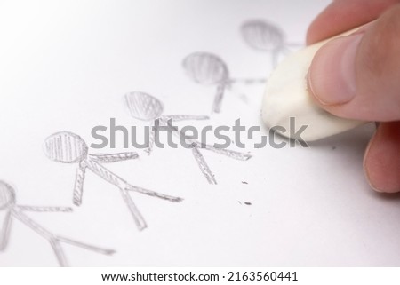 A hand with an eraser erases the painted men Royalty-Free Stock Photo #2163560441