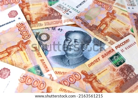 Chinese yuan banknote surrounded by russian rubles. Concept of economic cooperation between the China  and Russia, trading and support Royalty-Free Stock Photo #2163561215