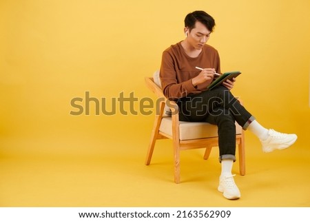 Creative young man listening to music in earbuds and drawing sketch on tablet computer Royalty-Free Stock Photo #2163562909