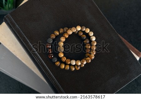 Two bracelets made of wood, lie on the books. High angle, detail