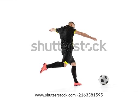 Professional male football soccer player in motion and action isolated on white background. Concept of sport, goals, competition, hobby, ad. Sportsmen wearing black football kit. Back view Royalty-Free Stock Photo #2163581595