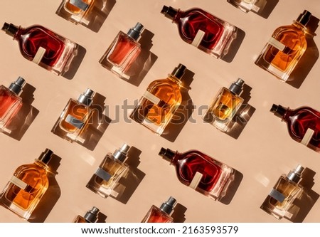 Pattern of different perfume bottles on a pastel beige background in the sunlight. Flat lay, top view. Luxury presentation mockup. Red, yellow and orange samples of aroma water Royalty-Free Stock Photo #2163593579